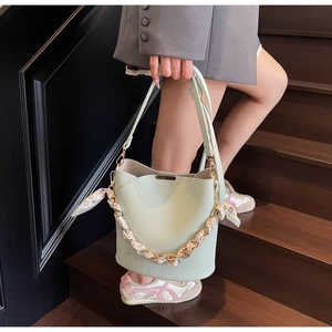 Detail of light mint green bucket bag with silk scarf handle on indoor wooden stairs