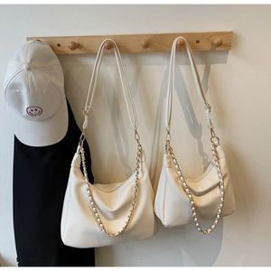 Detail of white hobo bags with litchi texture and gold chain on wooden hanger