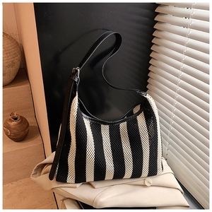 Détail de la bandoulière en cuir réglable sur un sac cabas en maille rayée noir et blanc