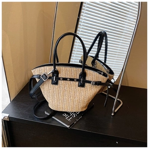 Detail of woven straw handbag with black leather trim and elegant metal buckle accent
