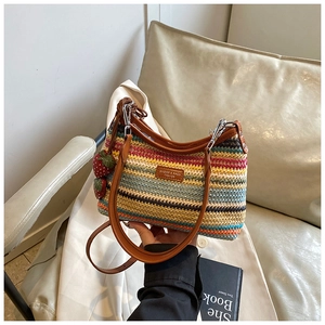 Détail du sac bandoulière tissé coloré avec lanières en cuir brun et bijou de fraise
