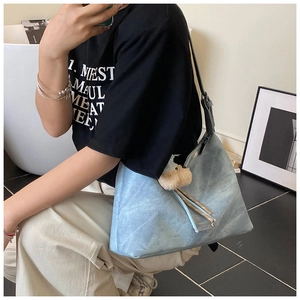 Détail d'un sac hobo bleu clair en forme de croissant avec un petit ours en peluche