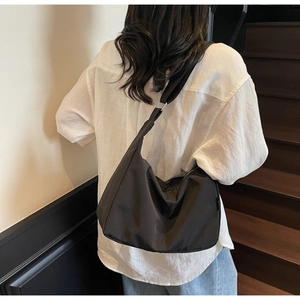Close-up of minimalist black canvas hobo bag with adjustable strap worn by model