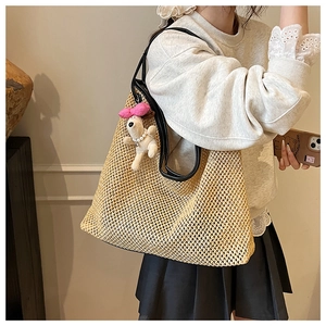Large beige woven straw tote bag with black leather straps and a cute plush dog charm