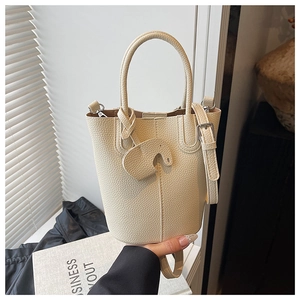 Detail of creamy white lychee leather bucket bag with cute elephant charm and handle
