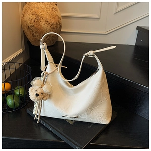 Détail du sac croissant blanc avec texture en cuir froissé et charm ours en peluche