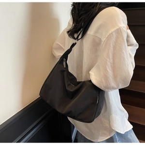 Close-up of black canvas hobo bag with DUIYAO side label and wide shoulder strap