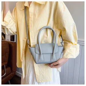Detail of light blue mini bucket bag with leather texture and silver metal hardware