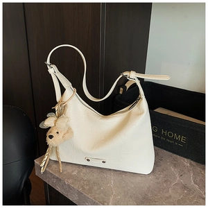 Détail du sac hobo blanc gaufré avec bandoulière réglable et accessoire ours en peluche