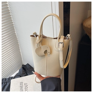 Detail of cream lychee texture bucket bag with cute elephant charm and silver hardware