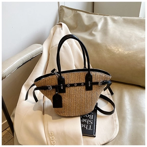 Detail of woven straw tote with black leather trim, metal eyelets and adjustable strap