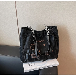 Gros plan du sac cabas plissé noir avec broderie chat et bandoulière chaîne