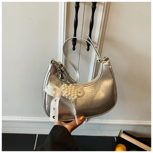 Detail of silver metallic crescent bag with soft pleated texture and pearl lace bow charm
