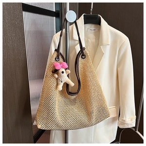 Detail of straw tote bag with brown leather strap and cute puppy plush charm
