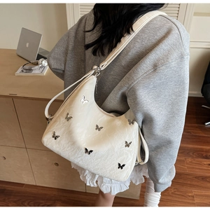White crescent underarm bag featuring butterfly metal accents and marble texture detail