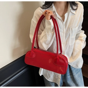 Detail view of bright red rectangular shoulder bag with slim double straps and smooth finish