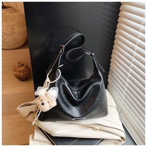 Détail du sac bandoulière en cuir PU plissé noir avec logo et charm ours en peluche