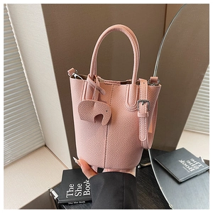 Detailed macro view of pink litchi grain leather bucket bag with cute elephant charm