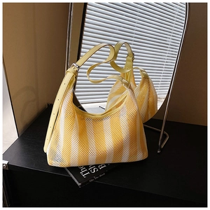Détail du sac cabas en maille rayée jaune avec bandoulière en cuir sur surface noire