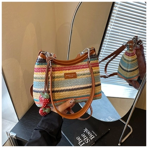 Détail du sac bandoulière tissé arc-en-ciel avec pendentifs fraises sur étagère