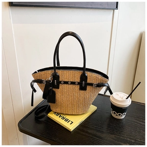 Detail of woven straw tote bag with black leather trim and handles on dark wooden table