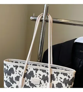 Detail shot of a large cow print tote bag with long smooth shoulder straps for women