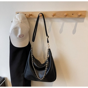 Close-up of black lychee grain leather hobo bag with gold metal chain on a hook