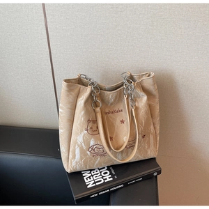 Détail du cabas beige avec illustration de chat et bandoulière en chaîne sur des livres