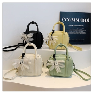 Detail of four colorful mini crossbody bags with floral charms on display stands