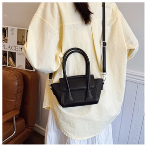 Close-up of black lychee grain leather mini tote bag shown on a model for size perspective