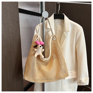 Detail of woven straw tote bag featuring creamy white trim and cute plush dog charm