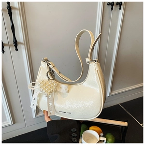 Detailed texture of off-white ruched patent leather bag with pearl heart and lace bow