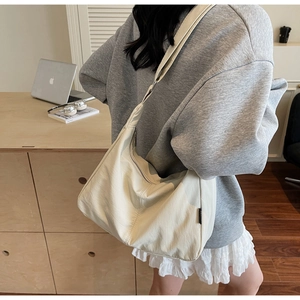Detail of soft cream-white crescent shoulder bag with smooth texture and zipper closure
