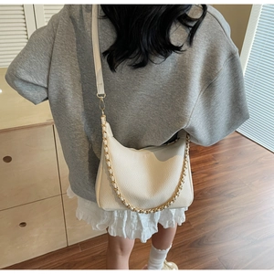 Over-the-shoulder view of a white lychee-textured crescent bag with chain detail