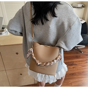Detail view of khaki bucket bag with floral scarf chain handle and leather strap
