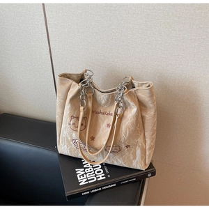 Détail du sac cabas beige avec texture nuage, broderie chat et bandoulière chaîne