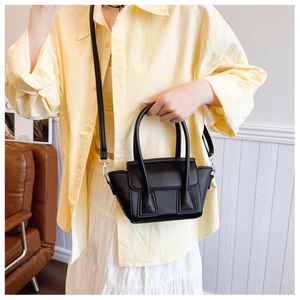 Detail of black pebbled leather handbag featuring twin handles and silver metal hardware