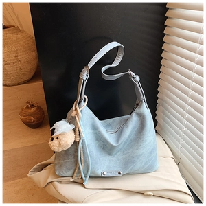 Gros plan du sac hobo bleu clair avec bandoulière réglable et breloque ourson