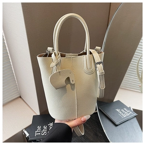 Detail of cream leather bucket bag with pebble texture and cute elephant charm