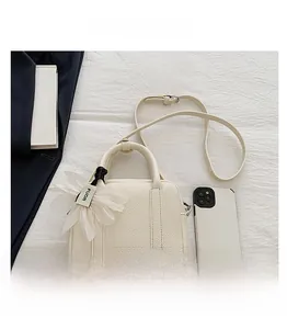 Size comparison of beige litchi pattern mini bag with smartphone and floral charm
