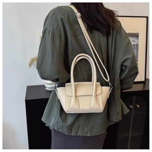 Detailed close-up of cream beige crossbody bucket bag with litchi grain texture and strap