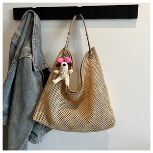 Detail of handwoven straw tote bag with brown leather strap and cute dog charm