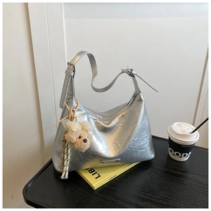 Détail du sac à main argenté en cuir froissé avec un joli pendentif de chiot