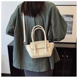Detailed back view of a beige lychee texture leather bucket bag held by a model