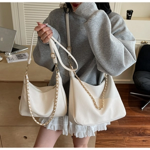 Detail of white lychee leather tote bags showing chain straps and adjustable shoulder bands