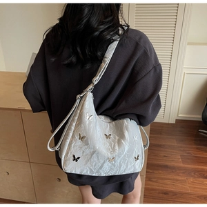 Silver textured hobo bag with metallic butterfly accents and adjustable shoulder strap
