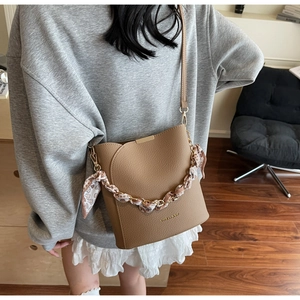 Détail du sac seau marron foncé avec texture lychee et décoration de chaîne en soie