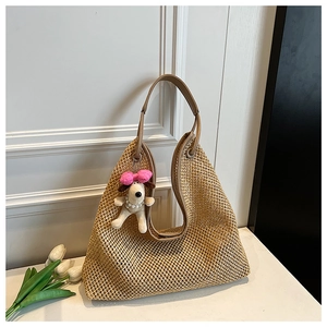 Detail of woven straw tote bag with brown leather handle and cute puppy charm