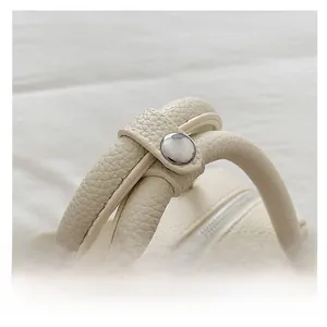Close-up of litchi grain leather handbags featuring dual cylindrical handles and silver snap button