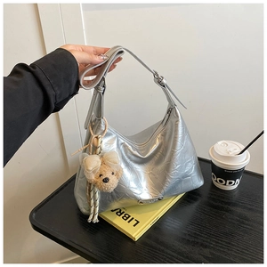 Sac fourre-tout argenté avec texture froissée et pendentif ours sur une table basse chic